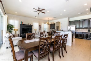 A spacious living room with a dark wood dining table, comfortable seating, a large flat-screen TV, and a ceiling fan. - Fs9620ha - Reunion Resort - 5 Bed 5.5 Baths Villa (Kissimmee)