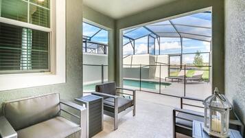 A spacious patio with a pool, outdoor seating, and large windows offering a view of the pool area.