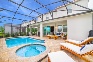 Una piscina con hidromasaje, sillas de descanso y un área de patio techada.