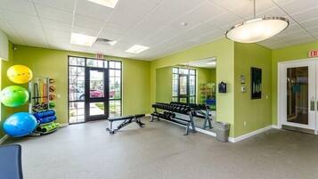 A gym with exercise equipment, a bench, and a mirror on the wall.
