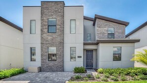 A modern two-story house with a stone facade, a grey roof, and a small front garden. - Fs9867ha - Storey Lake Resort - 9 Bed 5 Baths Villa (Kissimmee)