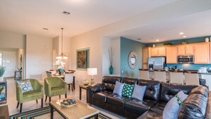 A living room with a black leather sofa, two green armchairs, a coffee table, and a dining area with a table and chairs. - Grh9174ha - Windsor Hills Resort - 4 Bed 4 Baths Villa (Kissimmee)