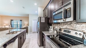 Una cocina moderna con encimeras de granito, electrodomésticos de acero inoxidable y salpicadero de azulejos.
