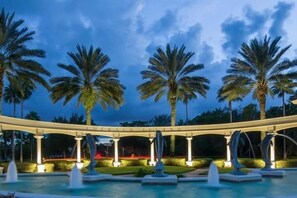 A pool area with palm trees, a covered walkway, and a dolphin sculpture. - Ffv10150ha - Emerald Island Resort - 7 Bed 4 Baths Villa (Kissimmee)