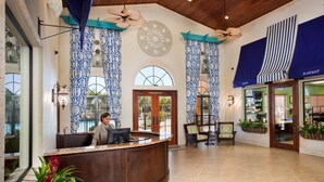A reception area with a wooden reception desk, patterned curtains, and ceiling fans. - Grh9252ha - Paradise Palms Resort - 6 Bed 5 Baths Villa (Kissimmee)