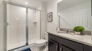A modern bathroom with a glass-enclosed shower, a white toilet, a vanity with a sink, and a potted plant. - Grh9264ha - Solara Resort - 4 Bed 4 Baths Townhome (Kissimmee)
