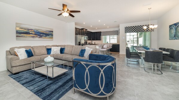 A modern living room with a sectional sofa, a coffee table, and a blue accent chair. - Grh9264ha - Solara Resort - 4 Bed 4 Baths Townhome (Kissimmee)