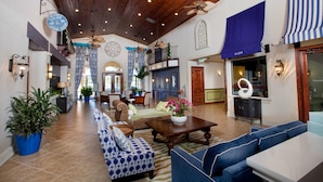 Eine geräumige Lobby mit hoher Decke, Holzbalken und einer Sitzecke mit blau-weißen Sofas.