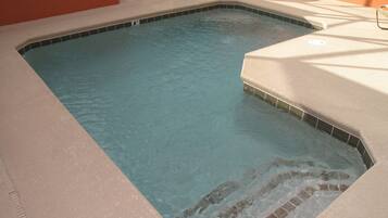 A rectangular hot tub with a tiled edge and a small waterfall feature.