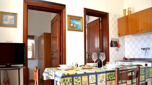 A dining area with a table set for two, a television, and wooden cabinets. - Tanoshii Holiday Home on the Ground Floor With Outdoor Space and Parking Space (Melendugno)