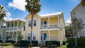 A row of two-story townhouses with balconies, a central entrance, and a well-maintained lawn.