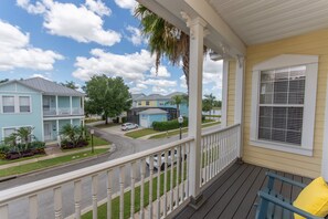 A porch with a view of a residential street, a covered area with a railing, and a yellow building. - Fsv10255ha - Reunion Resort - 4 Bed 3.5 Baths Townhome (Kissimmee)