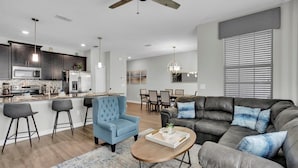 A modern living room with a sofa, a coffee table, and a blue armchair. - Grh9330ha - Storey Lake Resort - 4 Bed 3 Baths Townhome (Kissimmee)