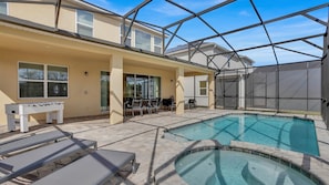 Uma área de piscina com hidromassagem, espreguiçadeiras e um terraço coberto.