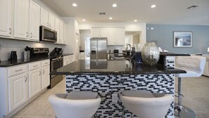 A modern kitchen with white cabinets, a black countertop, and a tiled backsplash. - Fs10375ha - Watersong - 6 Bed 5.5 Baths Villa (Davenport)