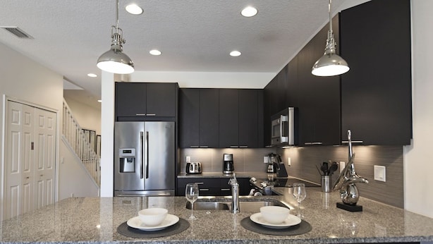 Una cocina moderna con muebles oscuros, electrodomésticos de acero inoxidable y encimeras de granito.