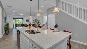 A modern kitchen with a large island, pendant lighting, and a view to the living area. - Fs10524ha - Windsor At Westside Resort - 7 Bed 6 Baths Villa (Kissimmee)
