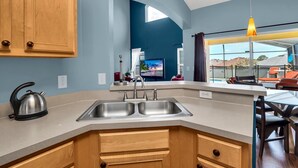 A modern kitchen with a large island, stainless steel sink, and wooden cabinets. - Fs11216ha - Emerald Island Resort - 5 Bed 4 Baths Villa (Kissimmee)