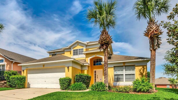 A two-story house with a yellow facade, a white garage door, and two palm trees in the front yard. - Fs11216ha - Emerald Island Resort - 5 Bed 4 Baths Villa (Kissimmee)