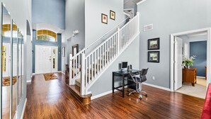 A spacious hallway with hardwood floors, a white staircase, and a dining area with a table and chairs. - Fs11216ha - Emerald Island Resort - 5 Bed 4 Baths Villa (Kissimmee)