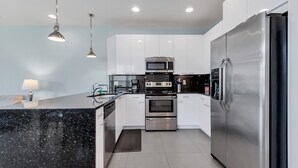 Una cocina moderna con armarios blancos, electrodomésticos de acero inoxidable y una encimera de granito negro.