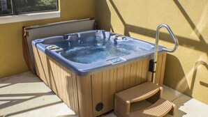 A hot tub with wooden steps and a metal faucet, placed on a patio with a yellow wall and a window in the background. - Ihr11318ha - Encantada Resort - 2 Bed 2.5 Baths Townhouse (Kissimmee)