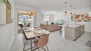 A modern kitchen with a dining area, a sofa, and pendant lighting. - Fs11330ha - Storey Lake Resort - 4 Bed 3 Baths Townhouse (Kissimmee)