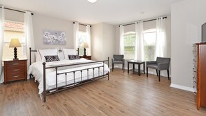 Ein Schlafzimmer mit Bett, Nachttischen, einem Sessel und einem Schreibtisch.