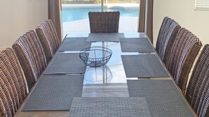 A dining area with a long table, wicker chairs, and a view of a swimming pool. - Ffv11368ha - Windwood Bay - 5 Bed 4 Baths Villa (Davenport)