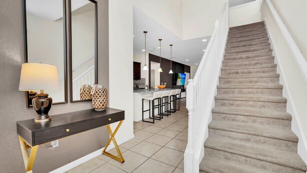 A modern kitchen with a central island, a dining area with bar stools, and a staircase leading to an upper level. - Fs11374ha - Windsor At Westside Resort - 7 Bed 6 Baths Villa (Kissimmee)