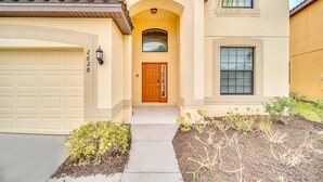 A two-story house with a beige facade, a wooden front door, and a garage. - Fs11371ha - Veranda Palms Resort - 6 Bed 4 Baths Villa (Kissimmee)