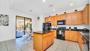 A modern kitchen with wooden cabinets, a black refrigerator, a microwave, and a dishwasher. - Fs11371ha - Veranda Palms Resort - 6 Bed 4 Baths Villa (Kissimmee)