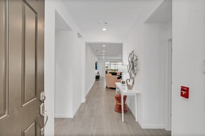 A modern hallway with a door, a white console table, and a red fire alarm. - Fs11377ha - Veranda Palms Resort - 15 Bed 14.5 Baths Villa (Kissimmee)