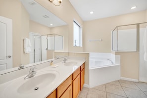 Une salle de bain moderne avec deux lavabos, un grand miroir, une baignoire et des meubles en bois.