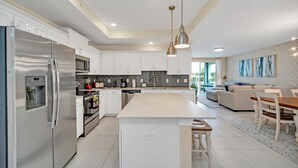 Una cocina moderna con una isla central, electrodomésticos de acero inoxidable y una zona de comedor con mesa y sillas de madera.