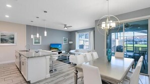 A modern kitchen with a central island, white cabinetry, and a dining area with a large table and chairs. - Fs11384ha - Storey Lake Resort - 4 Bed 3 Baths Townhouse (Kissimmee)