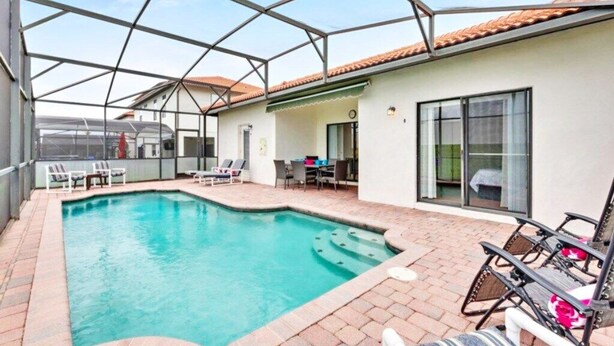Ein Pool mit Liegestühlen, eine überdachte Terrasse und ein Gebäude mit einem Ziegeldach.