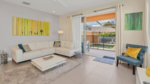 A modern living room with a sectional sofa, a blue armchair, and a glass door leading to a balcony. - Fs11372ha - Serenity - 3 Bed 3 Baths Townhouse (Clermont)