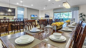A spacious dining area with a long wooden table set for a meal, surrounded by wooden chairs. - Fs11243ha - Windsor At Westside Resort - 8 Bed 6 Baths Villa (Kissimmee)