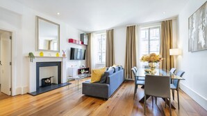 Una sala de estar moderna con chimenea, un sofá, una mesa de comedor con sillas y un televisor montado en la pared.