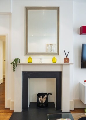 A modern living room with a fireplace, a large mirror, and a shelf with decorative items. - Mayfair`s Finest: Modern 2 bedroom apartment! (Greater London)