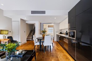 Una cocina moderna con un refrigerador negro, electrodomésticos de acero inoxidable y piso de madera.