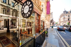 A street view with a prominent clock, storefronts, and a pedestrian walkway. - Mayfair`s Finest: Modern 2 bedroom apartment! (Greater London)