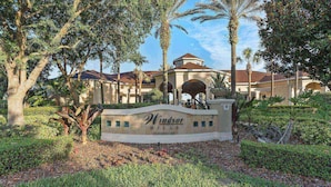 A sign for Windsor Hills Clubhouse surrounded by trees and a building with a dome roof. - It11510ha - Windsor Hill - 2 Bed 2 Baths Condo (Kissimmee)