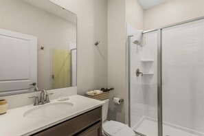 A bathroom with a white sink, mirror, and toilet, a glass shower enclosure, and a towel rack.