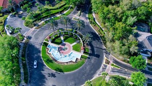 An aerial view of a roundabout with a central fountain, surrounded by palm trees and greenery. - Grh14421ha - Emerald Island Resort - 5 Bed 3 Baths Villa (Kissimmee)
