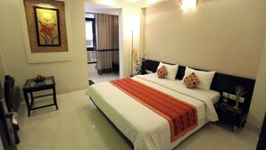 Habitación de hotel con una cama grande, una mesita de noche, una lámpara de noche, un cuadro en la pared y vistas al balcón.