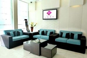 A hotel lobby with two sofas, a coffee table, and a TV screen displaying the hotel name. - Hotel Saar Inn (New Delhi)