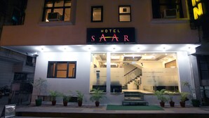 Entrada de hotel con un cartel que dice "HOTEL SAAR", una escalera que da acceso al interior y plantas en macetas en la acera.