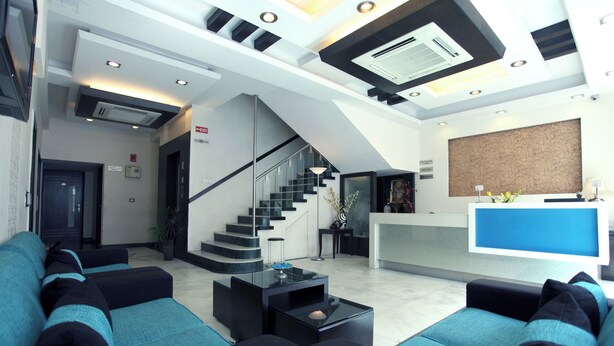 Un moderno vestíbulo de hotel con una recepción, una escalera y zonas de estar.